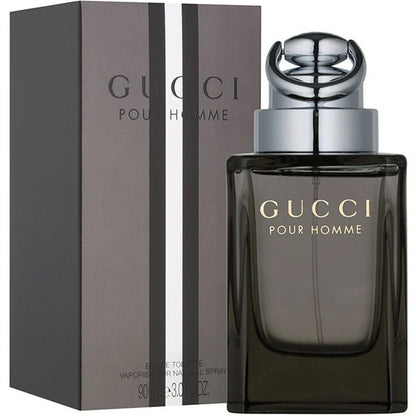 Gucci Pour Homme perfume bottle and its matching box, featuring a dark smoky glass bottle with gold lettering and a silver cap, next to a dark gray box with vertical silver stripes.